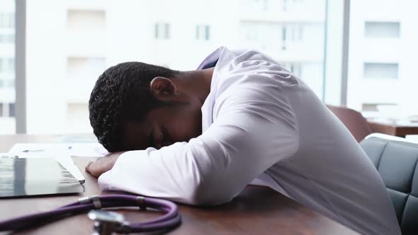 Tired African American Male Doctor Fall Sleeping at Desk on Working Place.