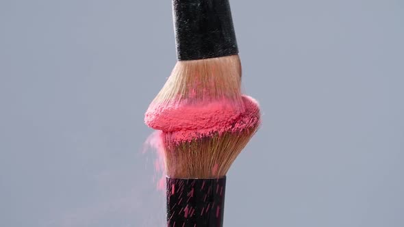 Make-up Brush with Pink Powder Splashes Explosion on Gray Background on Slow Motion