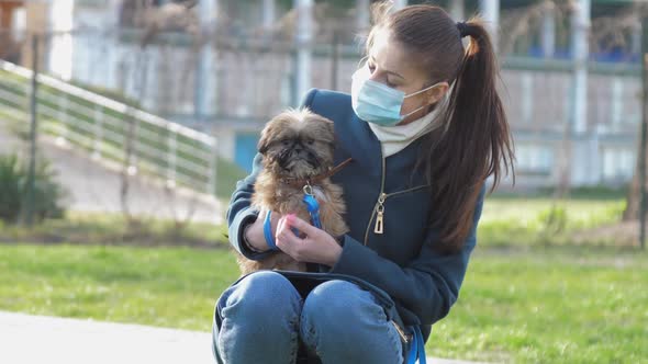 Lady with Ponytail Wears Medical Mask and Holds Shaking Dog