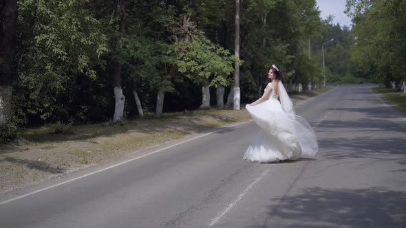 Slow Motion Bride in Long White Dress Dances on Road