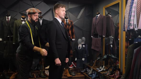 Bearded Tailor Dresses a Handsome Young Man in a Quality Handmade Suit in an Atelier. Creative Adult