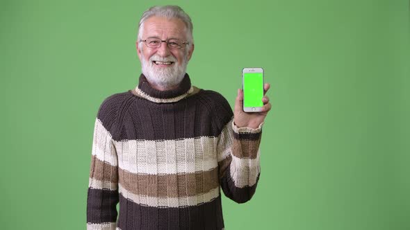 Handsome Senior Bearded Man Wearing Warm Clothing Against Green Background