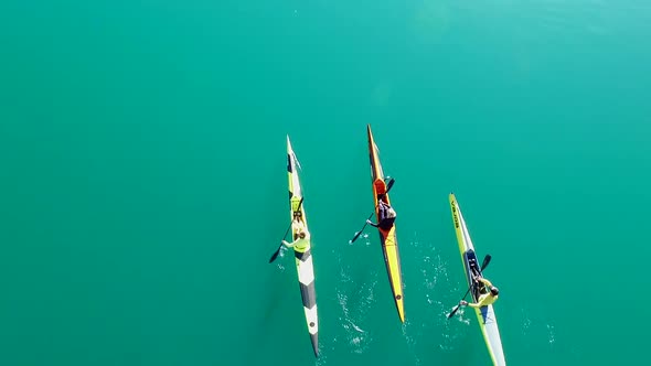 Three kayakers paddle in a scenic mountain lake.