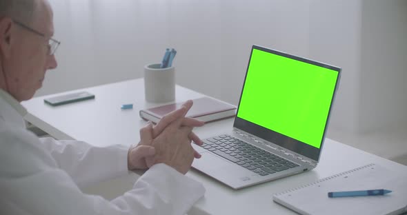 Male Physician Is Consulting Online, Looking at Green Screen of Laptop in Office of Clinic, Chroma