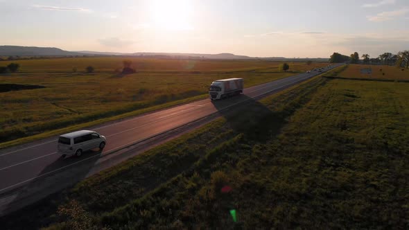 Aerial shot: vehicles, trucks and cars driving by road.