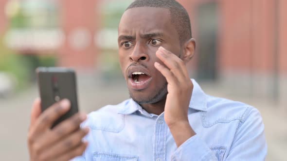 Outdoor Portrait of Upset African Man Having Loss on Smartphone