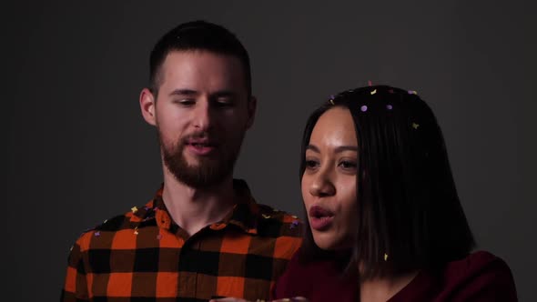 Couple blows confetti from the palm of the woman towards the camera - Slow motion