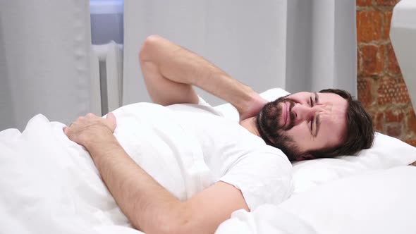 Beard Man with Neck Pain Trying to Relax in Bed