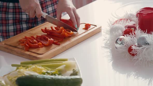 Young Woman Cutting Sweet Pepper While Standing at Table in Kitchen Interior.