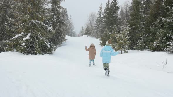 Happy Kids Running on Snowy Spruce Forest