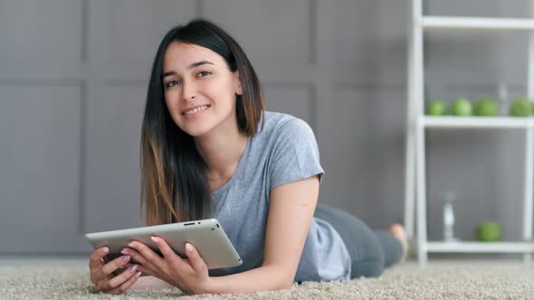 Young Happy Woman Lying on the Floor and Posing with Tablet Computer