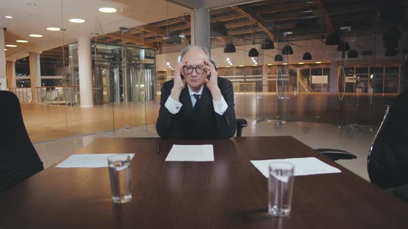 Tired Elderly Businessman Sitting Alone in Conference Room