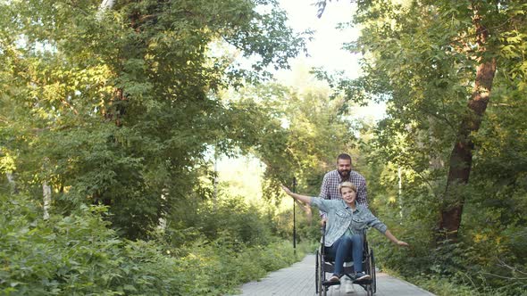 Man Rolls Emotional Disabled Woman in Wheelchair Who Spread Her Arms Like Wings Through Park