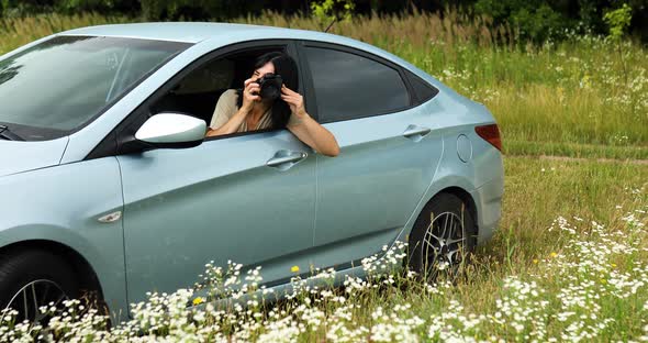 Woman photographer sitting in the car and photographing a flower field landscape