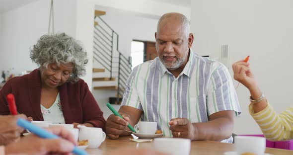 Happy senior diverse people drinking tea and playing bingo at retirement home