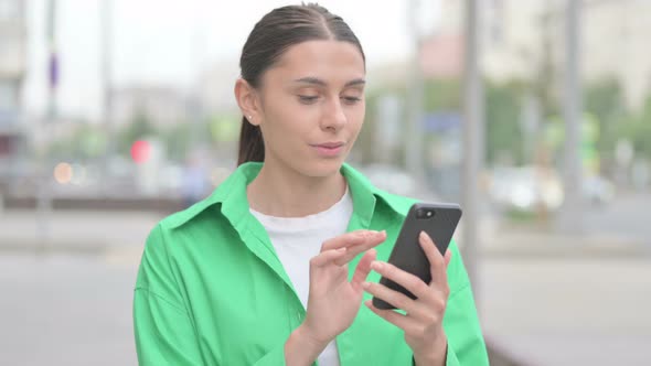 Hispanic Woman Browsing Internet on Smartphone Outdoor