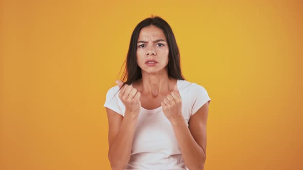 Young Woman Looking Very Nervous While Posing Against Orange Background