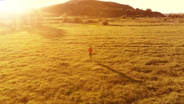 Flight Over Sport Man at Perfect Green Grass Meadow. Sunset in Mountain