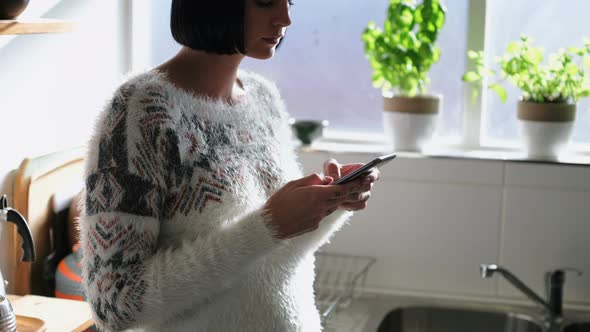 Woman Using Mobile Phone in Kitchen 