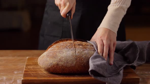 Female Baker Cutting Homemade Bread at Bakery