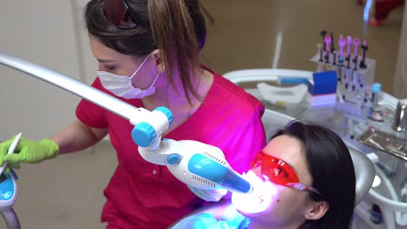 Young Woman Getting UV Whitening at the Dentist's Office By an Ultra Violet Machine