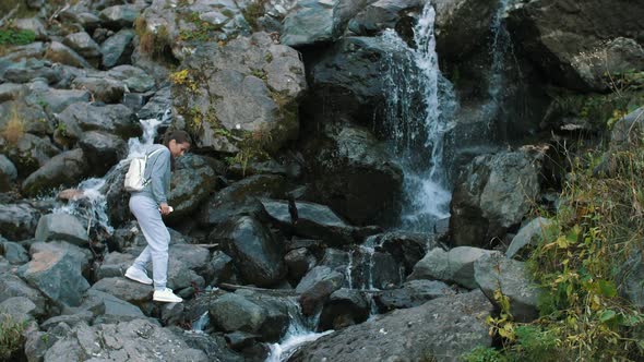 Woman Jumping Through Creek Near Waterfall