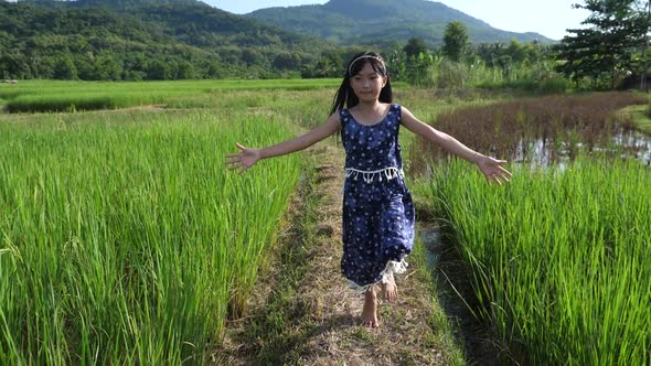 Asian Little Girl Running And Jumping In Rice Field