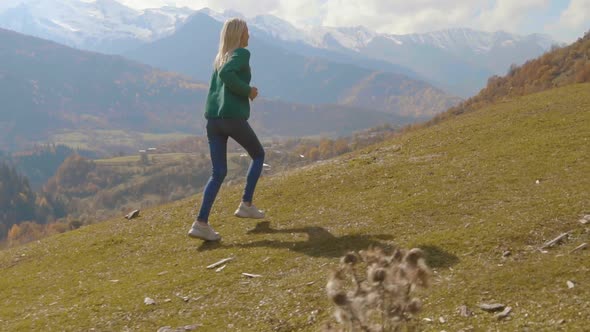 the camera follows a young beautiful woman who runs uphill down a slope