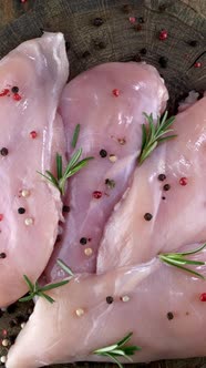 Fresh Raw Chicken Breast Fillets Sprinkled with Peppercorns and Rosemary Rotates Slowly