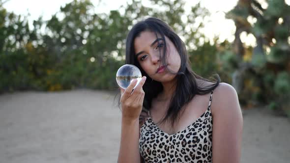 A gorgeous hispanic woman enchantress holding a magic crystal ball SLOW MOTION.