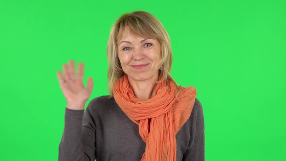 Portrait of Middle Aged Blonde Woman Is Waving Hand and Showing Gesture Come Here. Green Screen