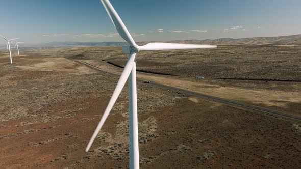 Drone Flying By Spinning Wind Turbine Propellers With Cars Driving In Background