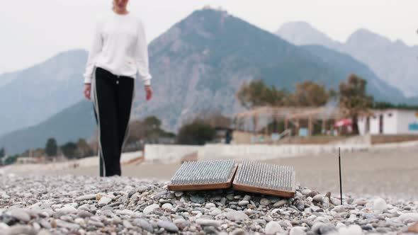 A Woman Walks to the Sadhu Board on the Seashore and the Incense Smoldering Nearby It