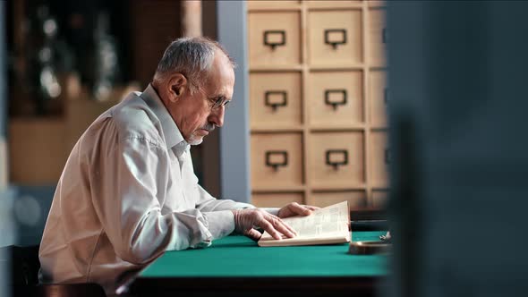 Elderly 70s Male Lawyer Reading Juristic Book Searching Legal Information Working at Public Library