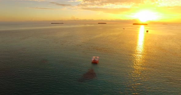 Aerial drone view of a man and woman having dinner on a floating raft boat at sunset