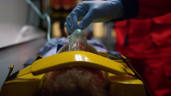Paramedic Hand in Glove Holding Oxygen Mask on Patient Face in Emergency Car