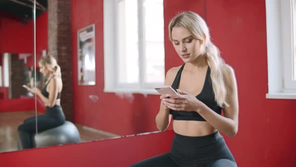 Beautiful Woman Using Smartphone in Fitness Club