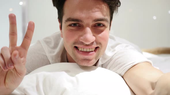 Victory Gesture by Man Lying in Bed