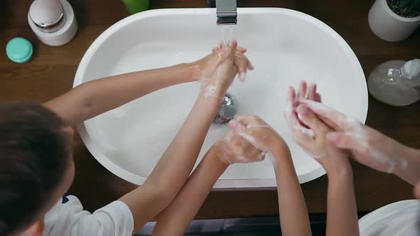 Two Boys and Adult Standing Near the Washbasin and Carefully Washing with Soap their Hands alt