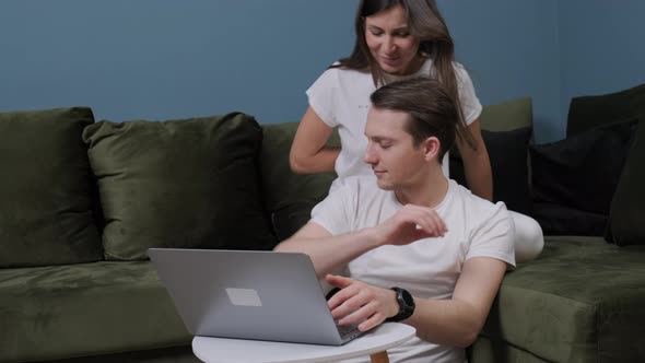 Young Man That Is Working at the Computer Receiving a Gift From His Wife