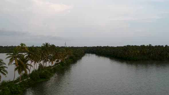 Beautiful aerial shot of a backwater canal, sunset,coconut trees ,water transportation,Clouds,tree l