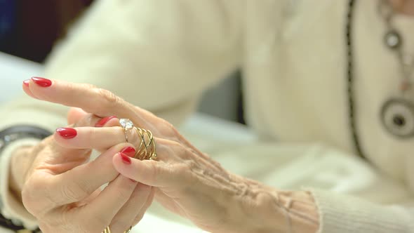 Woman Putting on Ring with Diamond.