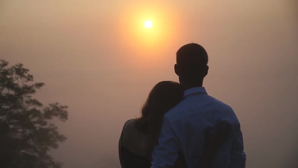 Young Couple Hugging and Admiring Scenic Sunset Landscape Together