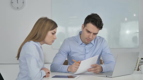 Business People Discussing Project Documents, Paperwork