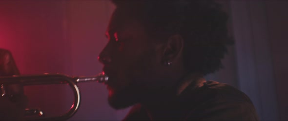 Close up of trumpeter playing in a room with smoke and red neon lights