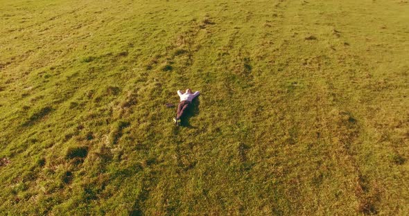 Low Orbital Flight Around Man on Green Grass with Notebook Pad at Yellow Rural Field.