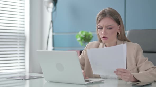 Businesswoman Upset While Reading Documents at Work