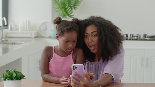 Happy Young Family of Two African American Mom and Daughter Having Fun Time at Home Using Mobile