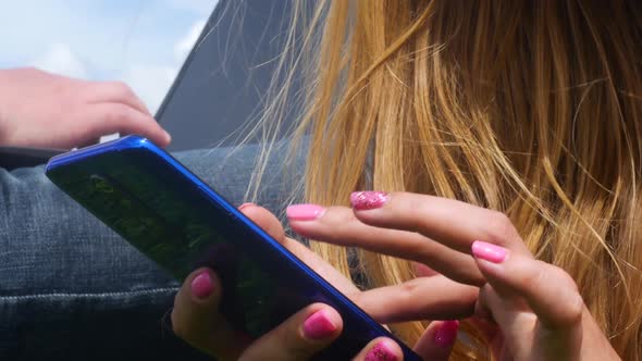 A Guy And A Girl Are Resting In The Park And Using Gadgets