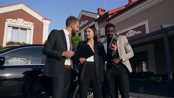 Team of Three Young Mixed-Race Office Workers Using Tablet Computer and Worker Documents